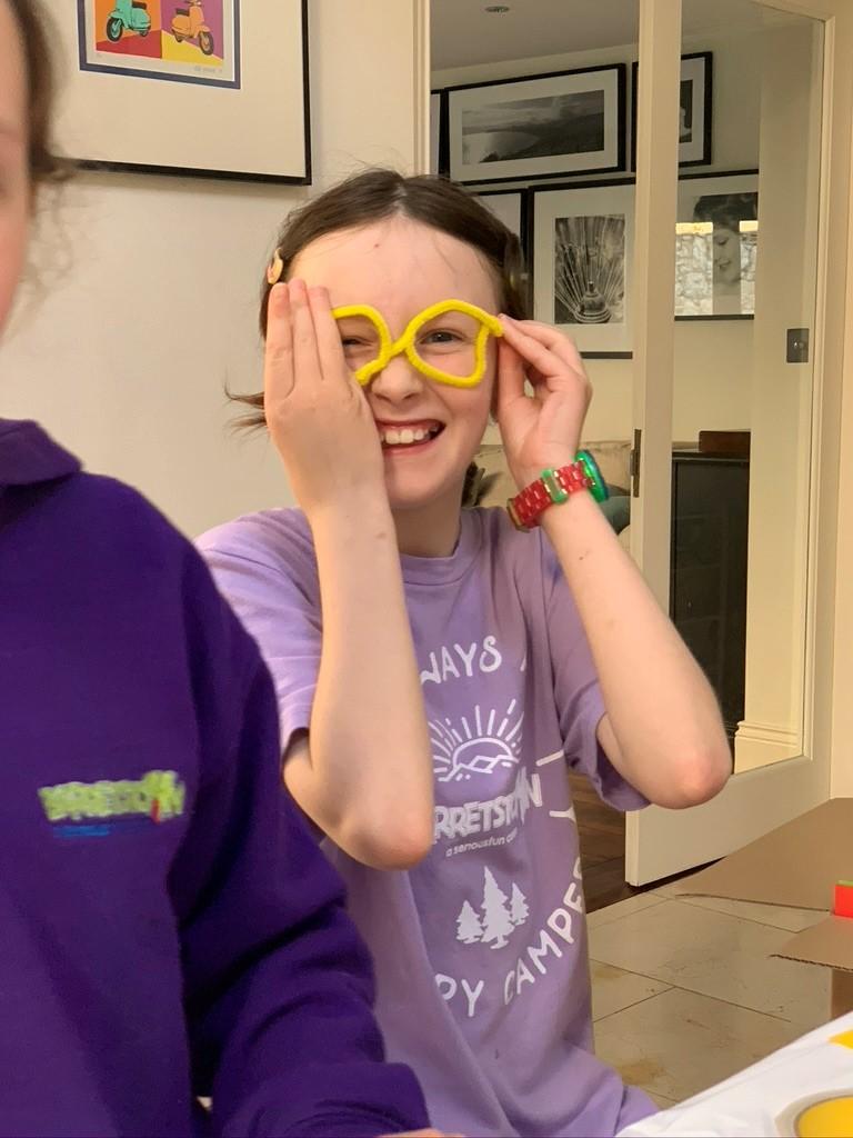 A young girl laughing, putting on yellow star shaped glasses