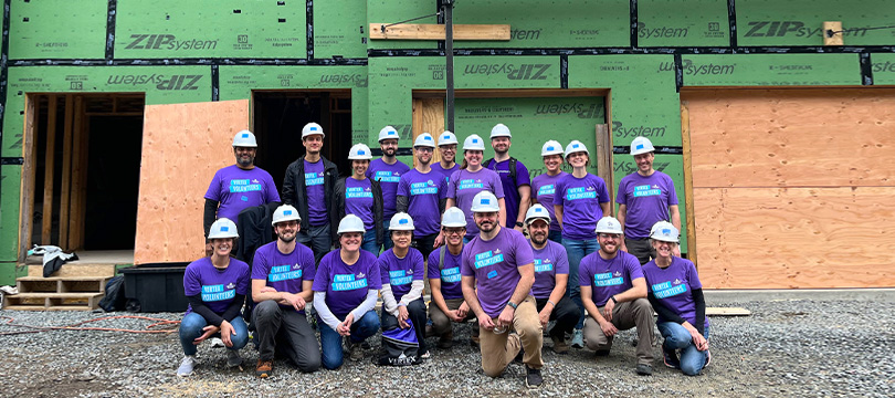 An image of a group of Vertexians wearing purple Day of Service shirts while holding up skateboards they helped design during our 2023 Day of Service.